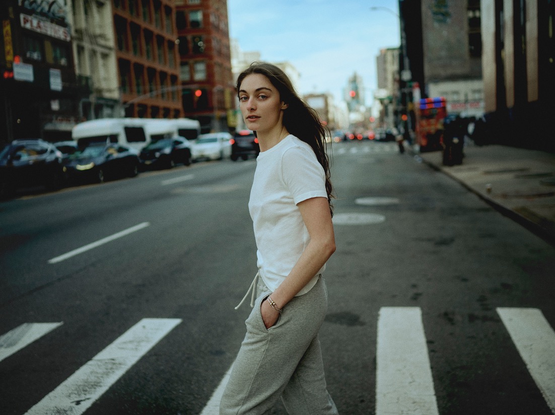 woman crossing the street in New York wearing a white t-shirt and sweatpants