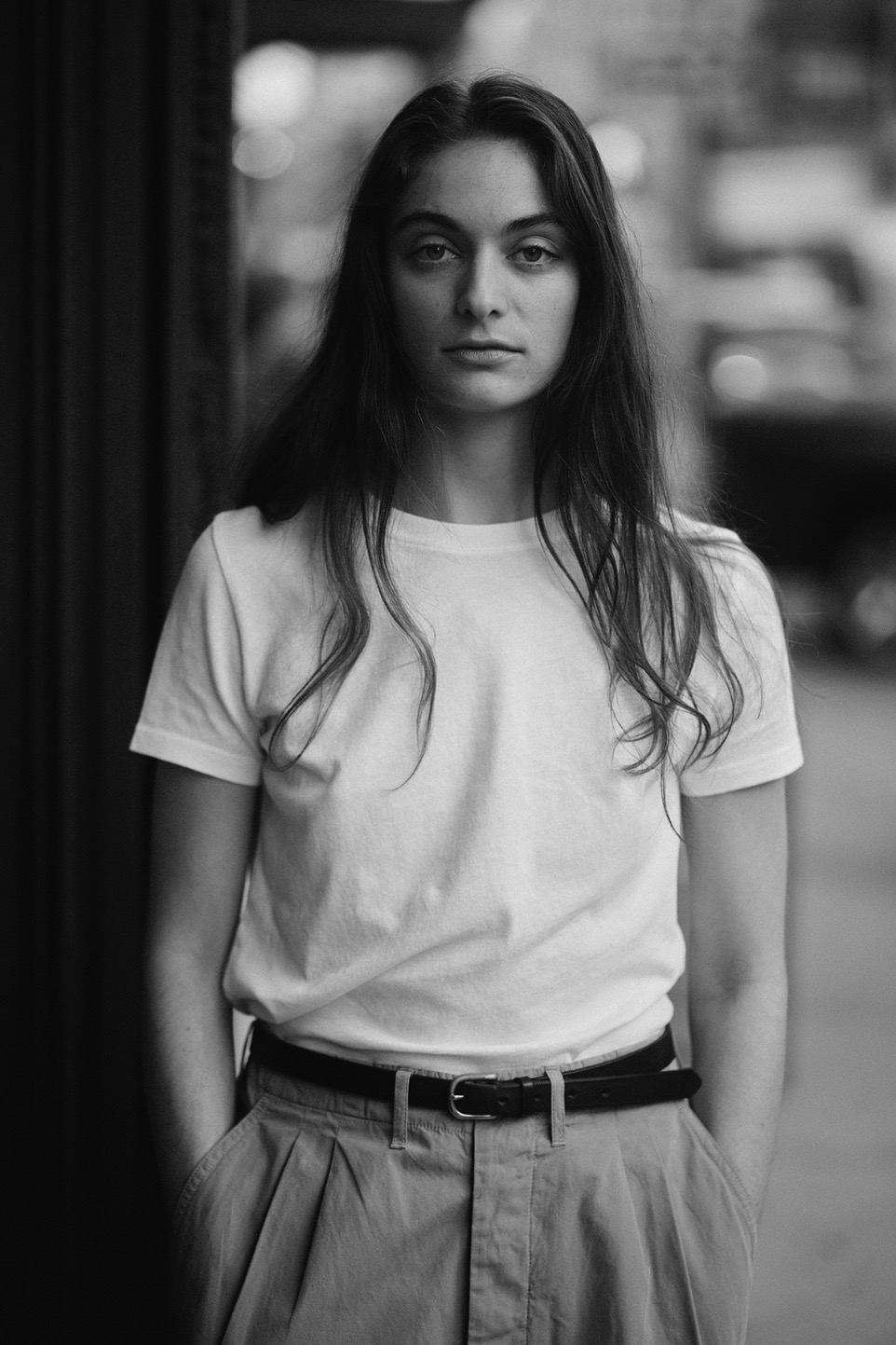 black and white photo of woman wearing a white t-shirt and pleated pants