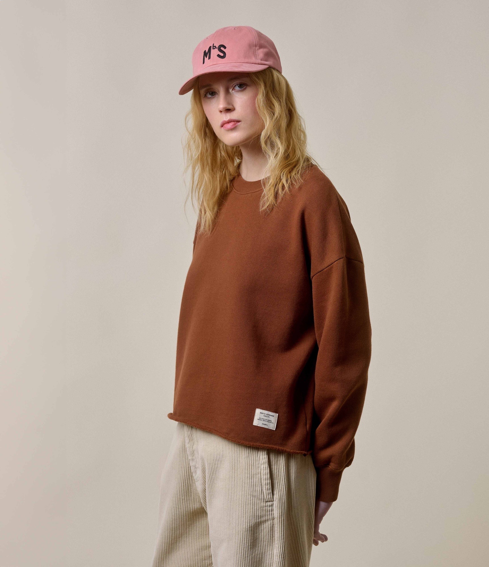 woman wearing brown sweatshirt with open edge and nature corduroy pants