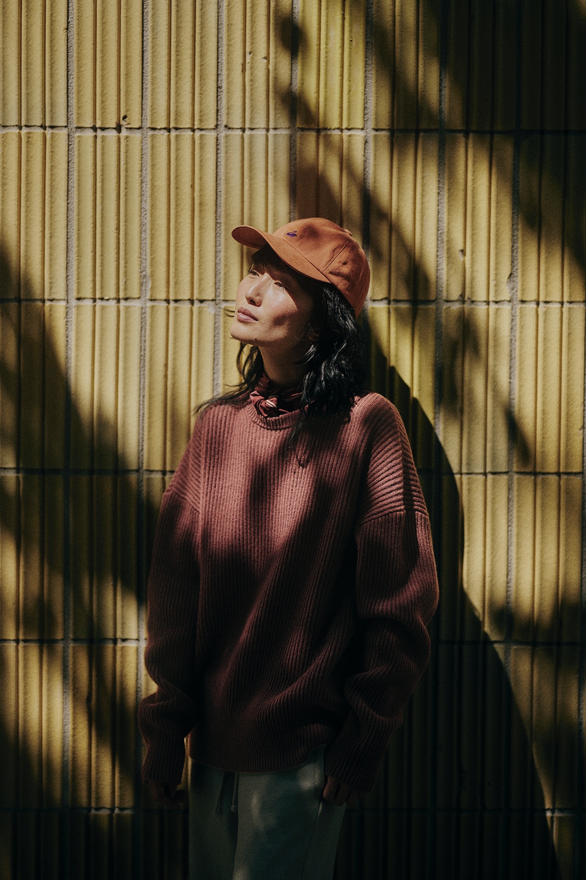 Woman wearing burgundy knit pullover, bandana and orange cap