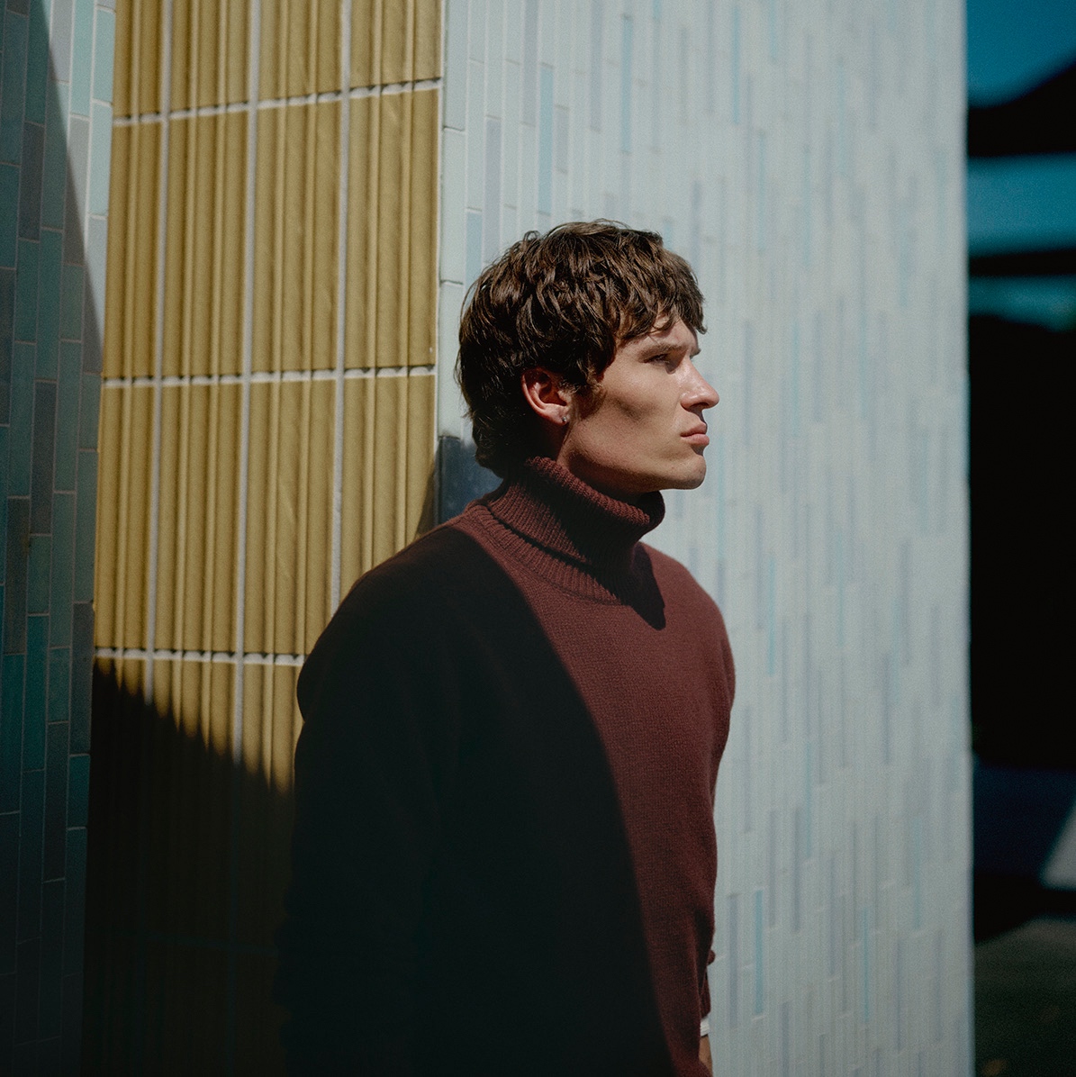 Man wearing burgundy turtleneck pullover in front of a wall