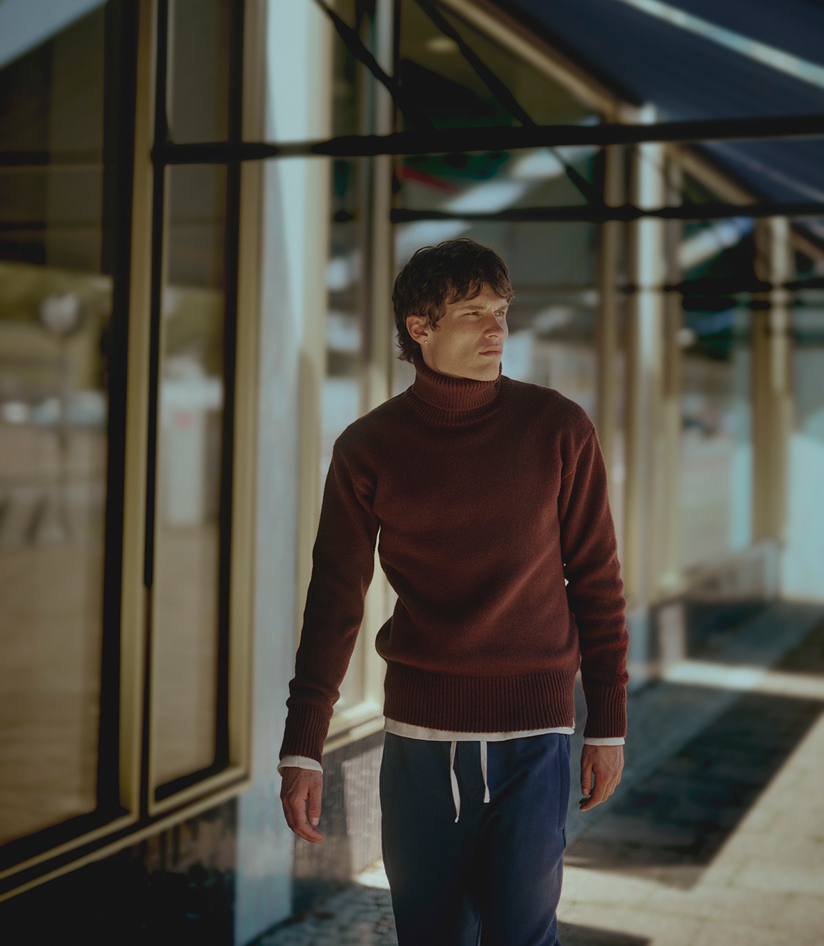 Man wearing burgundy turtleneck pullover and blue sweatpants in the street