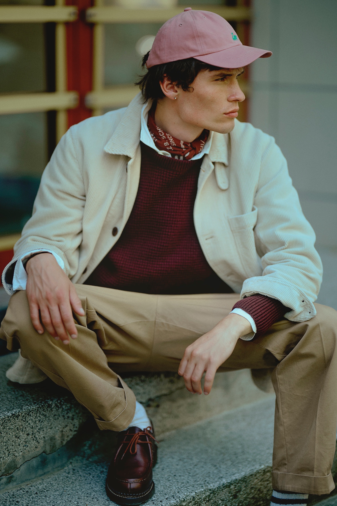 Man with cap and bandana wearing white corduroy jacket and burgundy waffle pullover over white shirt