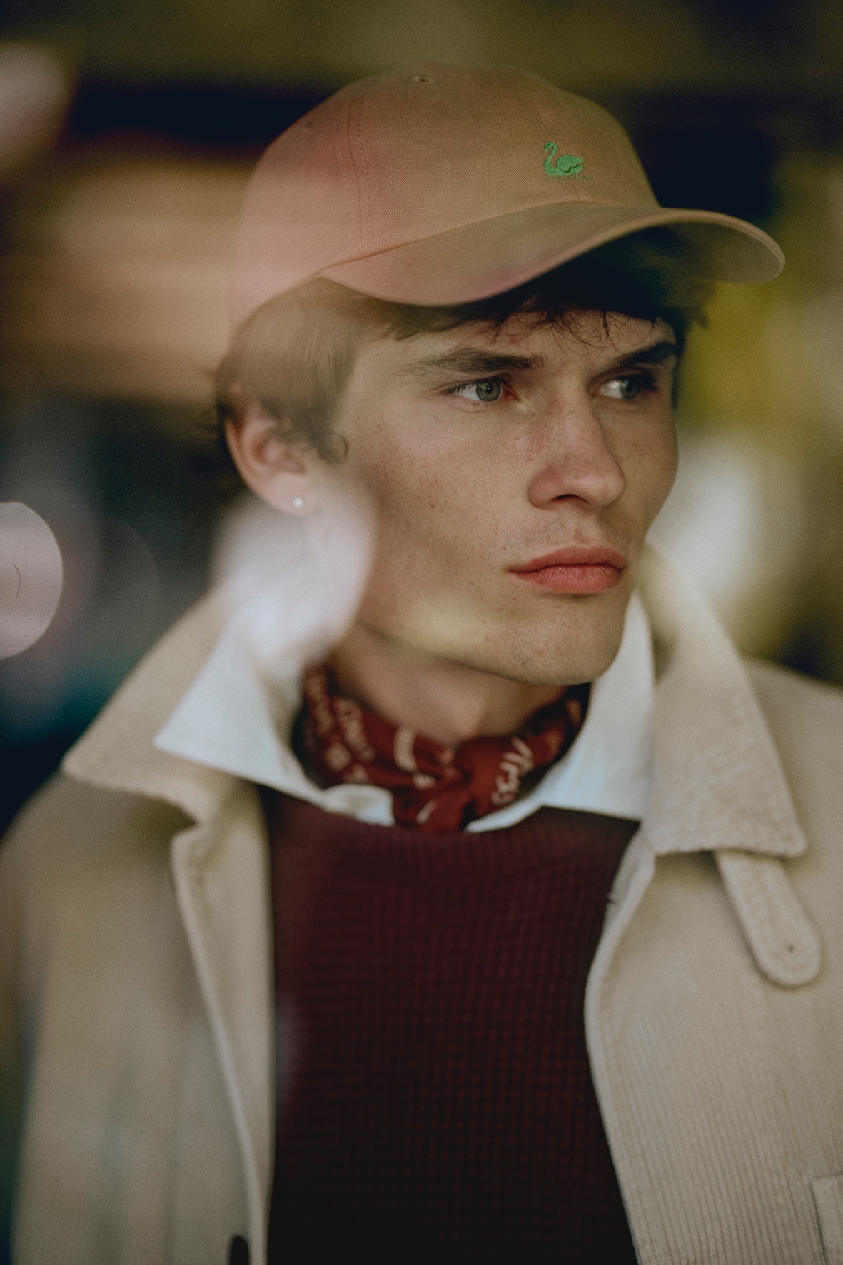 Man with pink cap and bandana wearing burgundy waffle pullover and white corduroy jacket over white shirt 