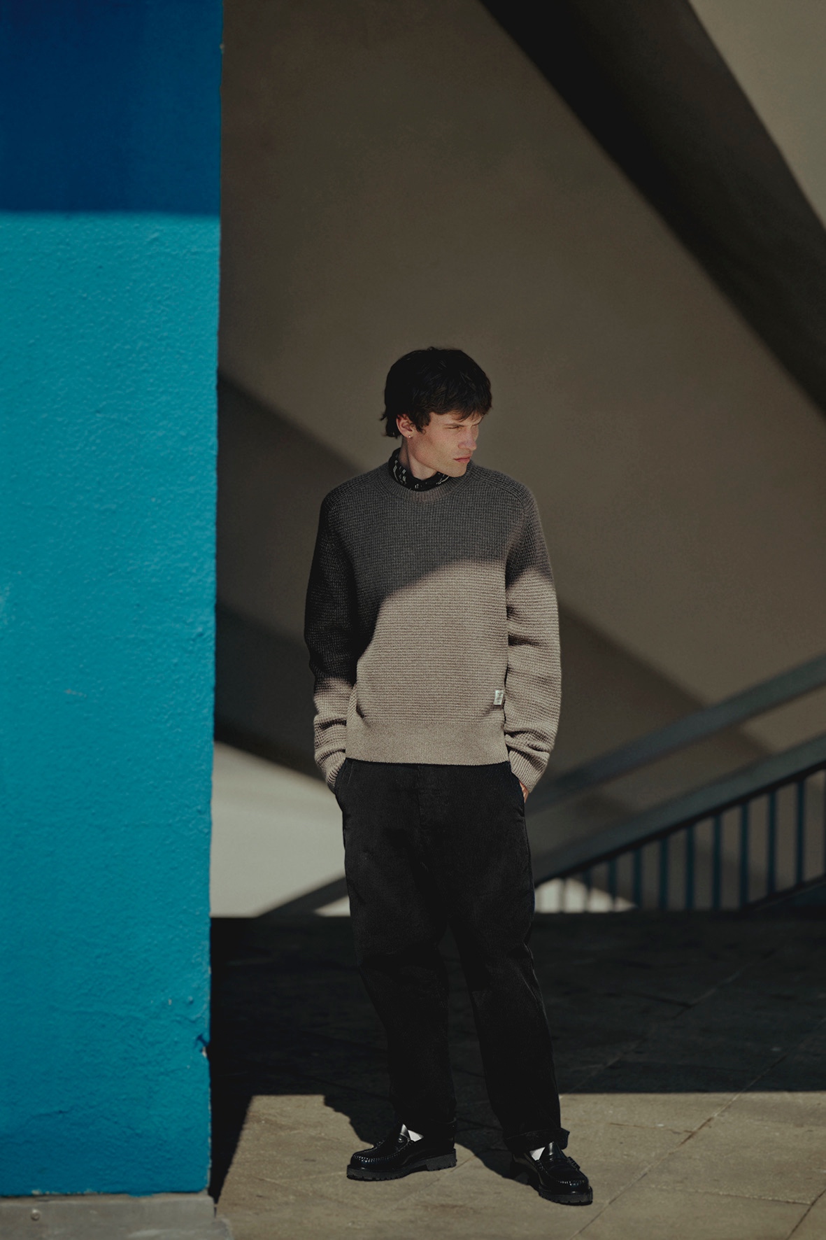 Man wearing grey crewneck pullover, black chino and bandana