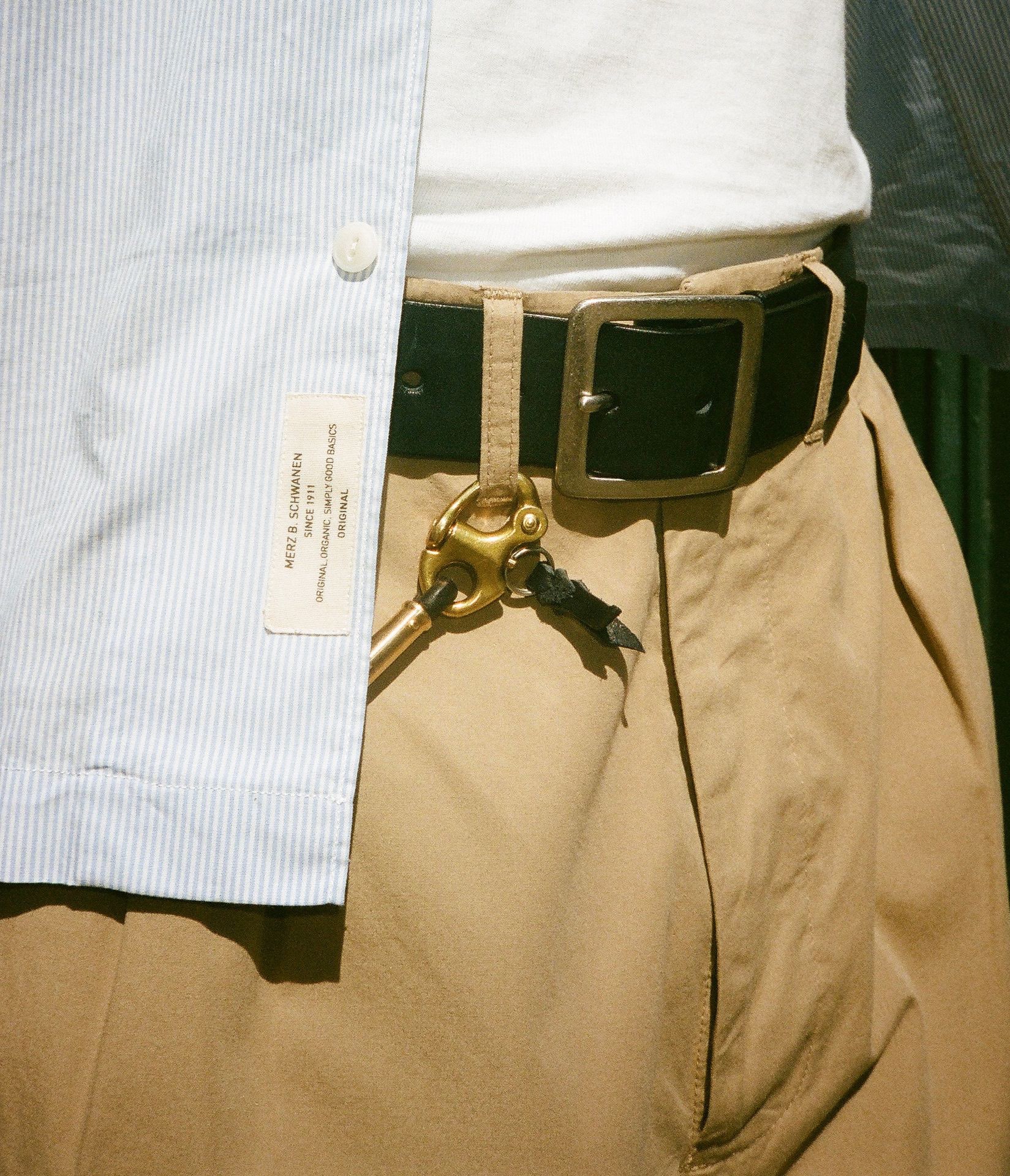 Man in striped shirt wearing black leather belt and keychain on khaki chino trousers