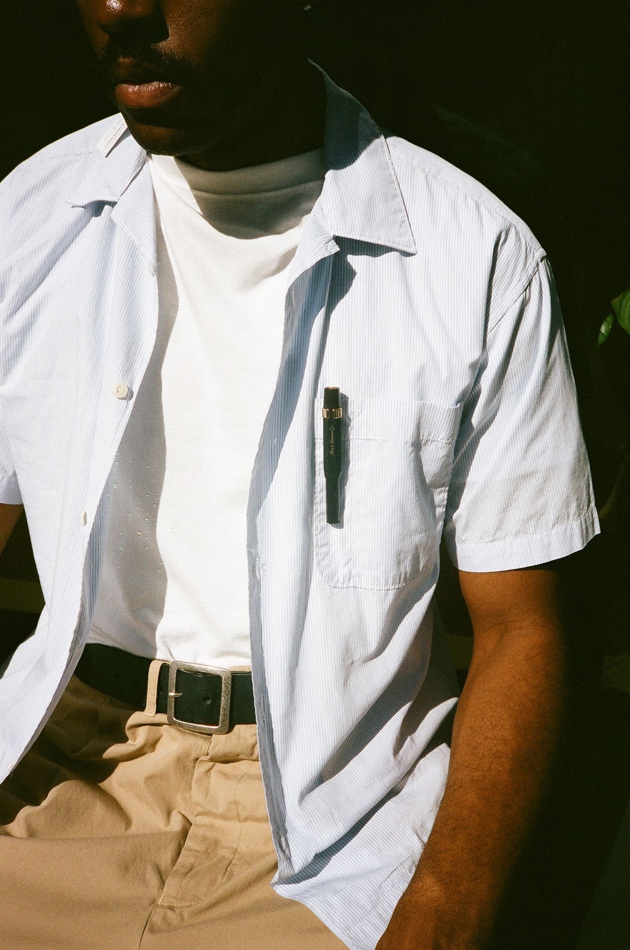 Man in striped shirt wearing black leather belt and keychain on khaki chino trousers