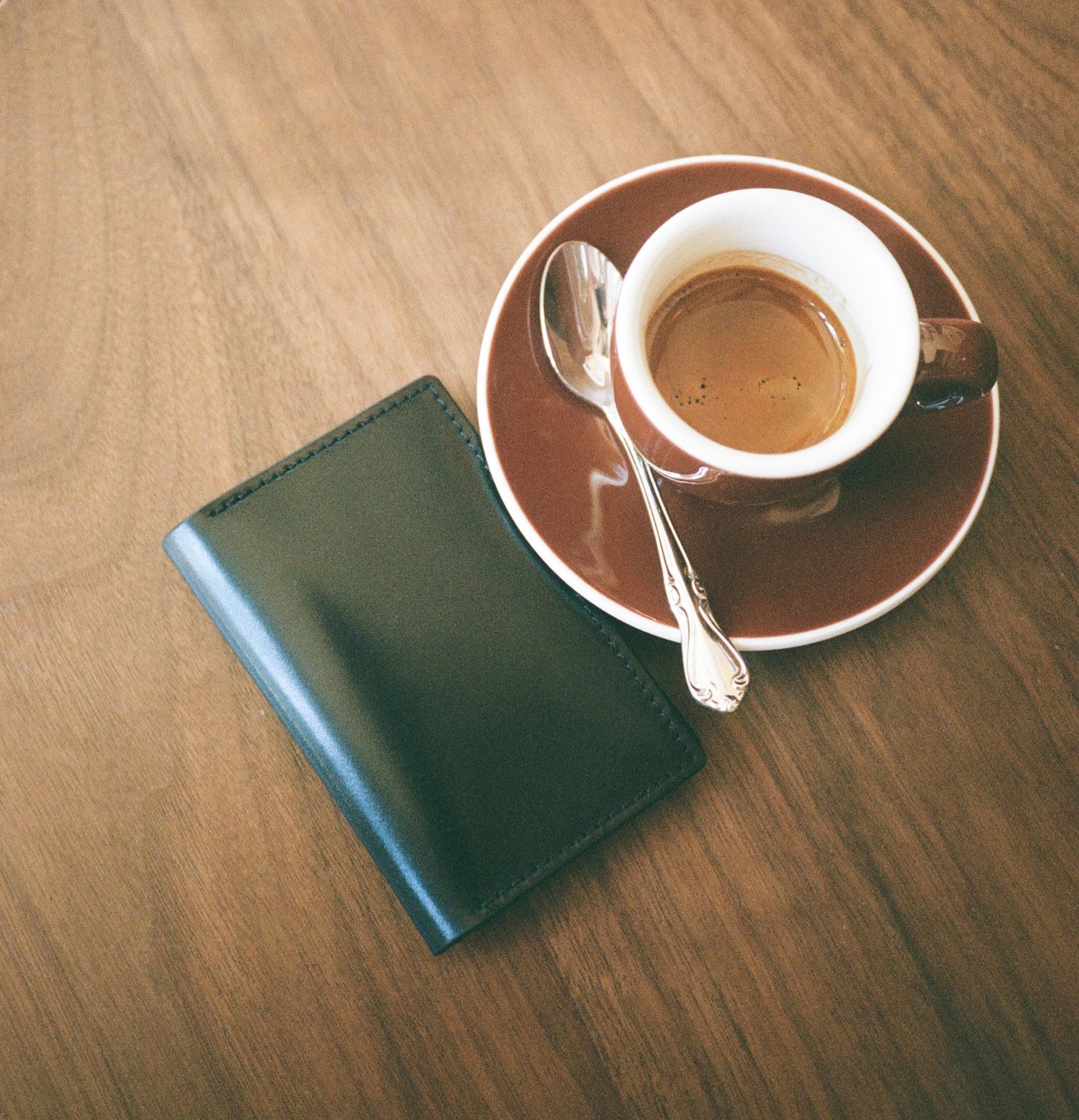 Black leather cardholder next to coffee on a table