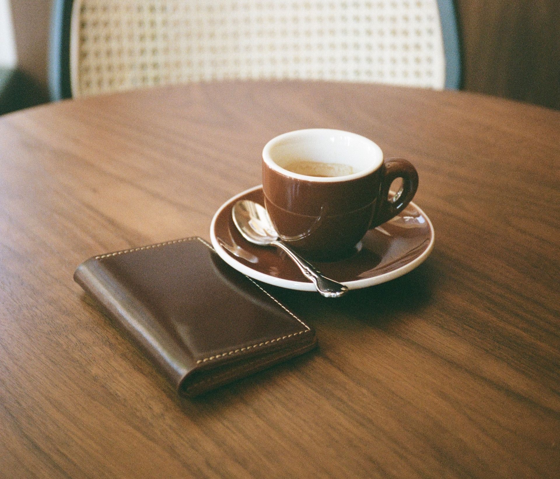 Brown leather cardholder next to coffee on a table