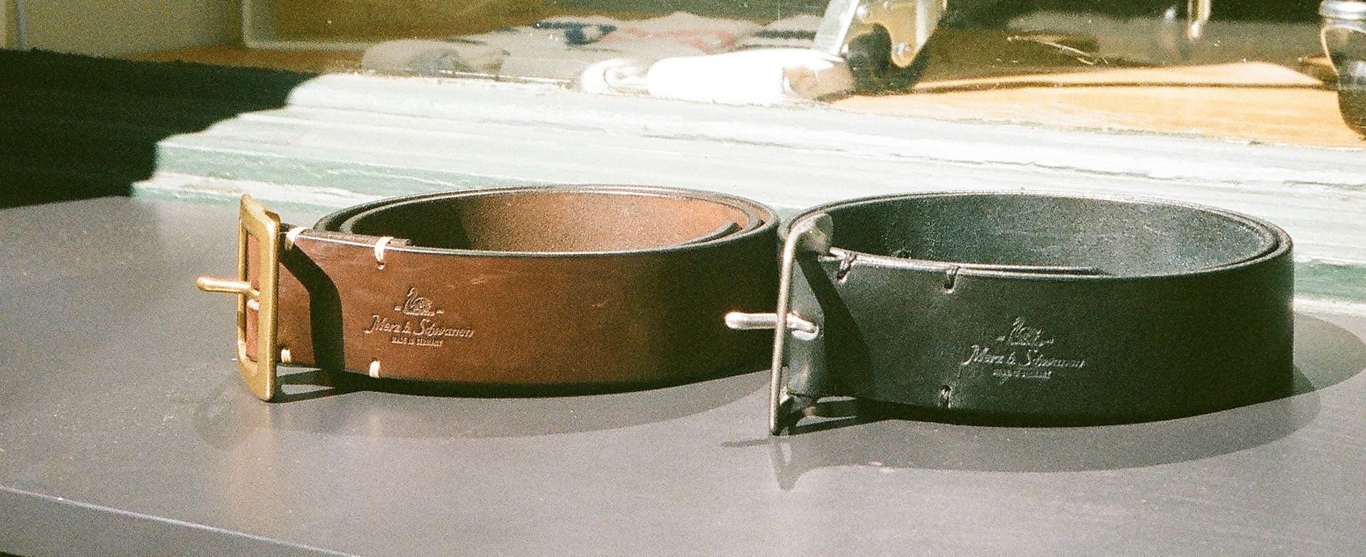 Brown and black leather belt in front of a window 