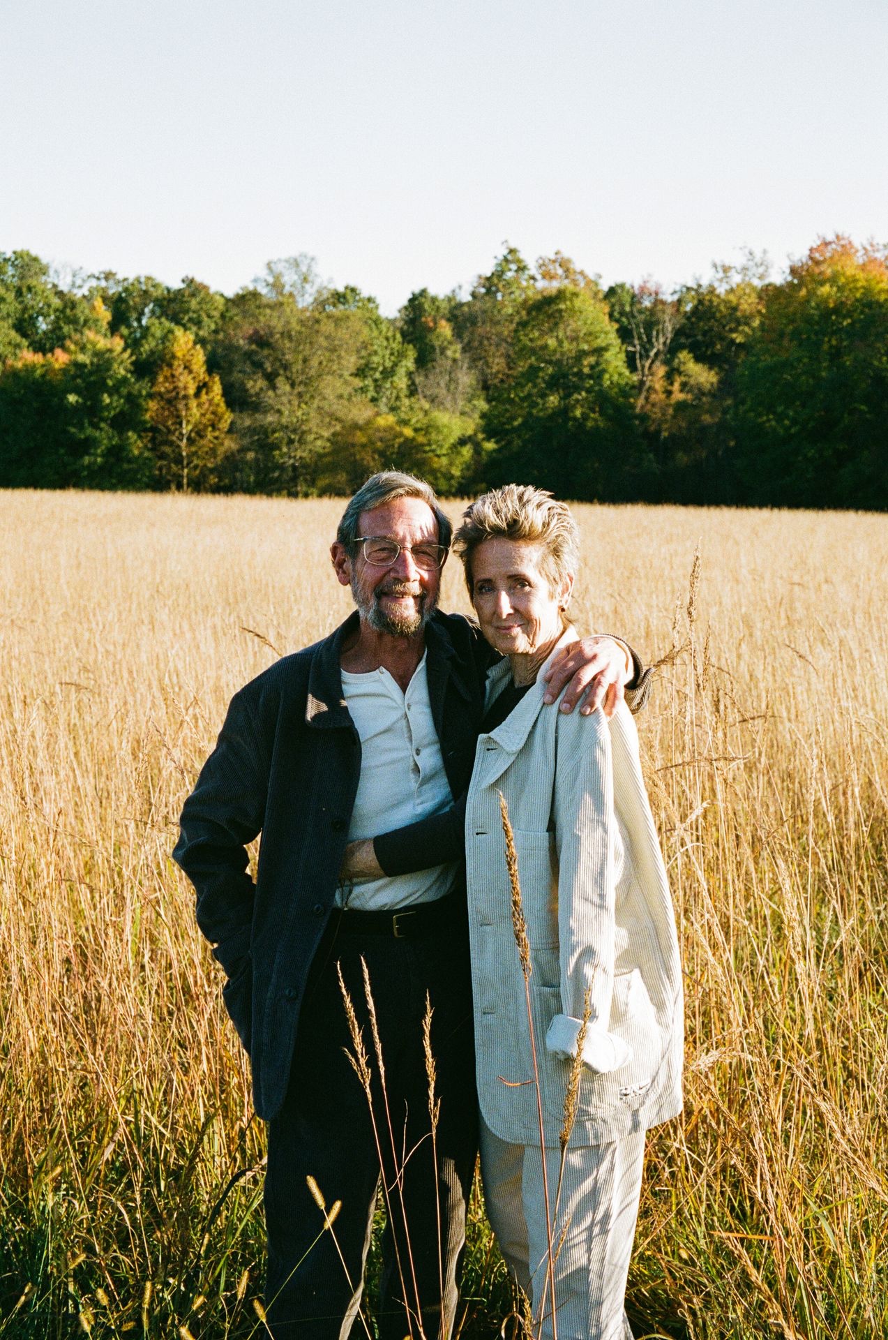 Couple wearing white and brown corduroy jackets standing in a field