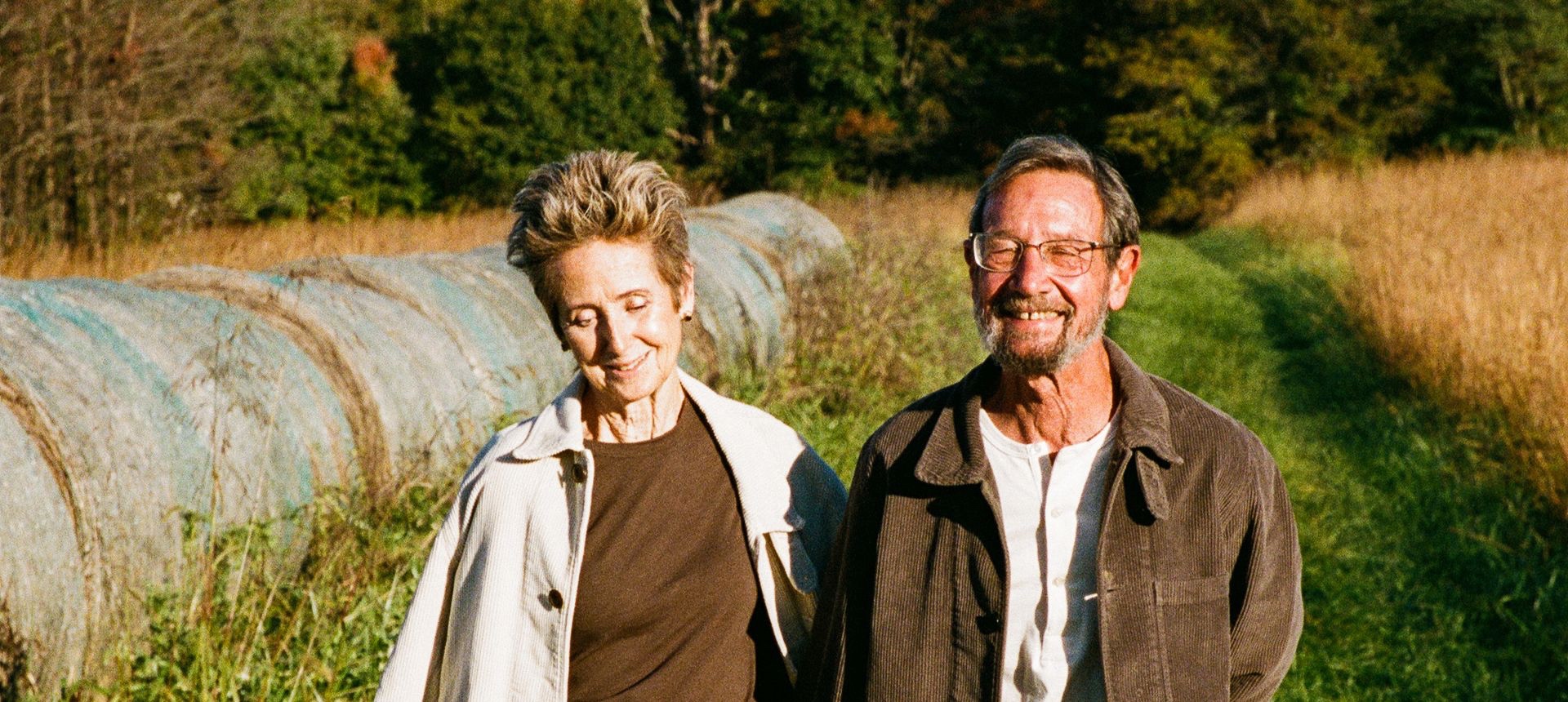 Couple wearing white and brown corduroy jackets walking through field