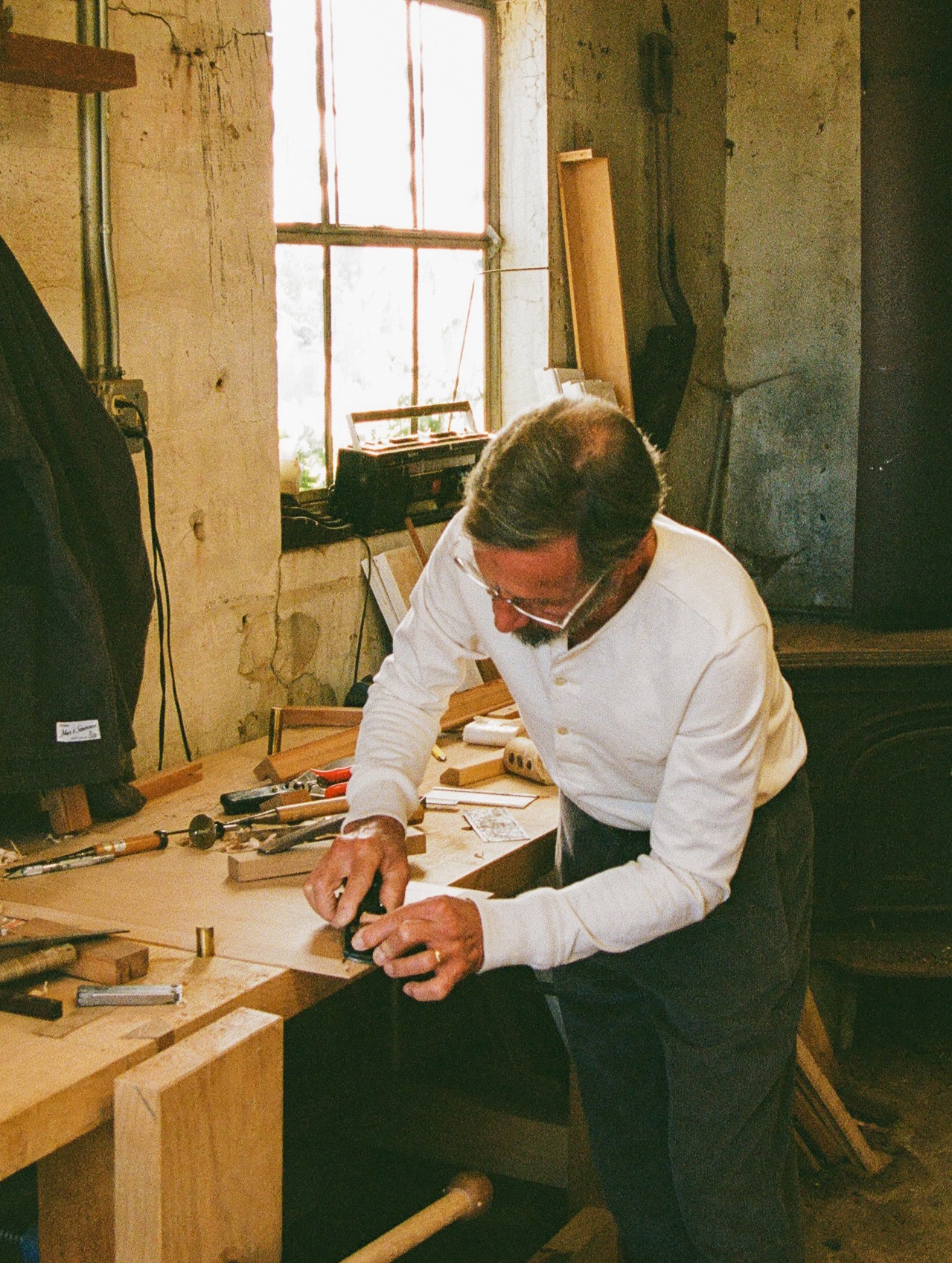 Man in his workshop wearing white longsleeved henley and corduroy trousers