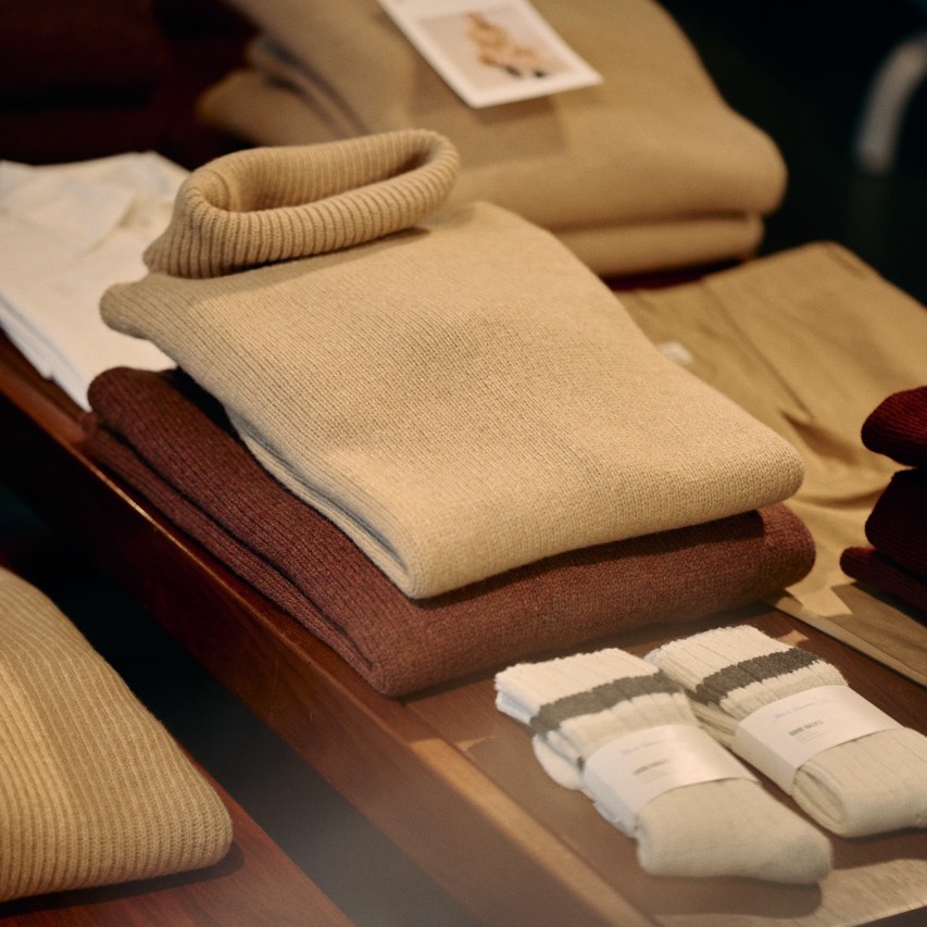 merino wool and cashmere pullovers and some pairs of socks laying on a table